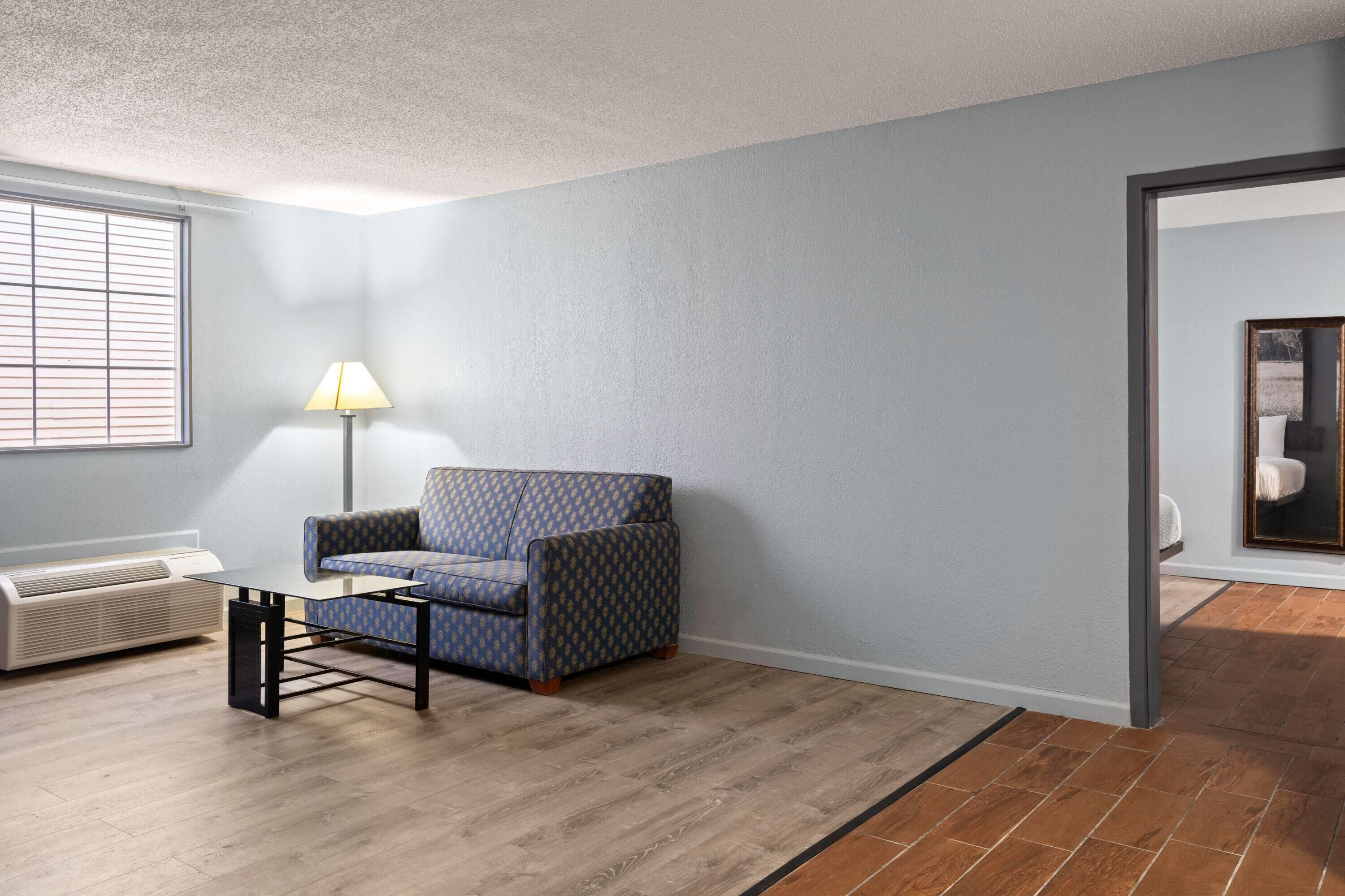 A room with a patterned sofa, a standing lamp, a radiator, and a tiled floor.