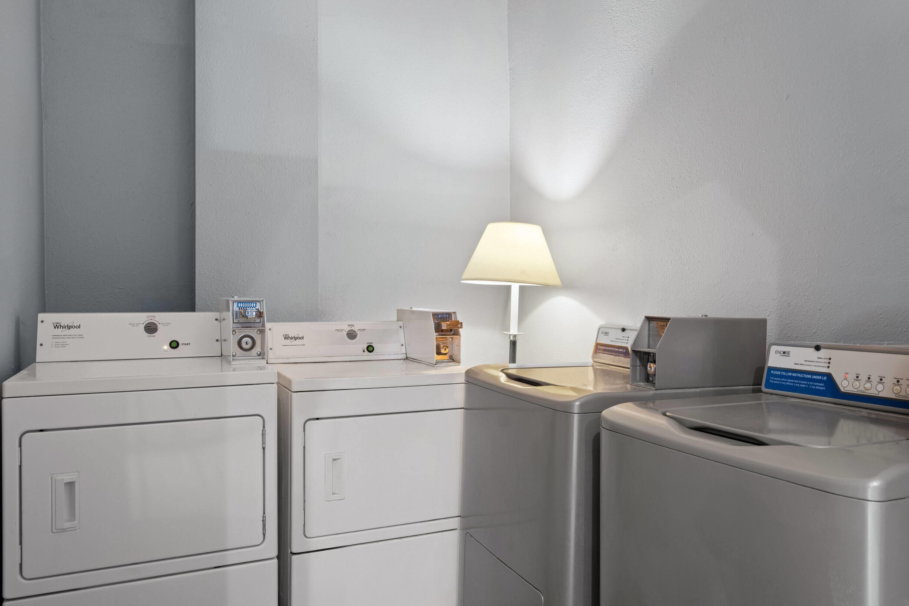 A laundry area with Whirlpool washers and dryers, a lamp, and a control panel.