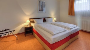 Ein Hotelzimmer mit einem großen Bett, zwei Nachttischen mit Lampen, einem gerahmten Bild an der Wand und einem Fenster mit Vorhängen.