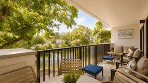 Un balcon aménagé avec du mobilier d’extérieur, une plante en pot et une vue sur les arbres et les bâtiments.