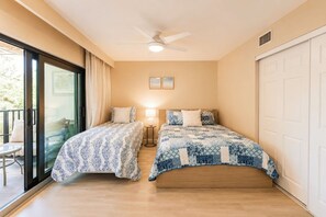 A bedroom with two beds, a ceiling fan, a nightstand with a lamp, and a sliding glass door to a balcony. - Park Shore Resort, BLDG G #241*Great Views* (Park Shore Resort)