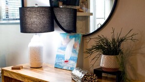 A wooden console table with a round mirror, a lamp, a framed painting, and decorative items.