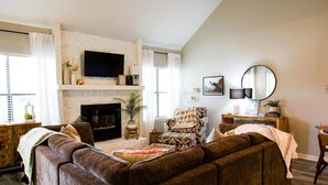 A living room with a fireplace, a sofa, a television, and a dining area.