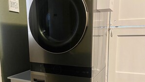 A stacked washer and dryer unit in a laundry room with a small white cabinet and a marble countertop. - Home in Anderson Township (Cincinnati)