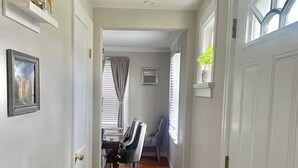 A hallway with wooden flooring, white walls, a chandelier, and a dining area with a table and chairs. - Home in Anderson Township (Cincinnati)