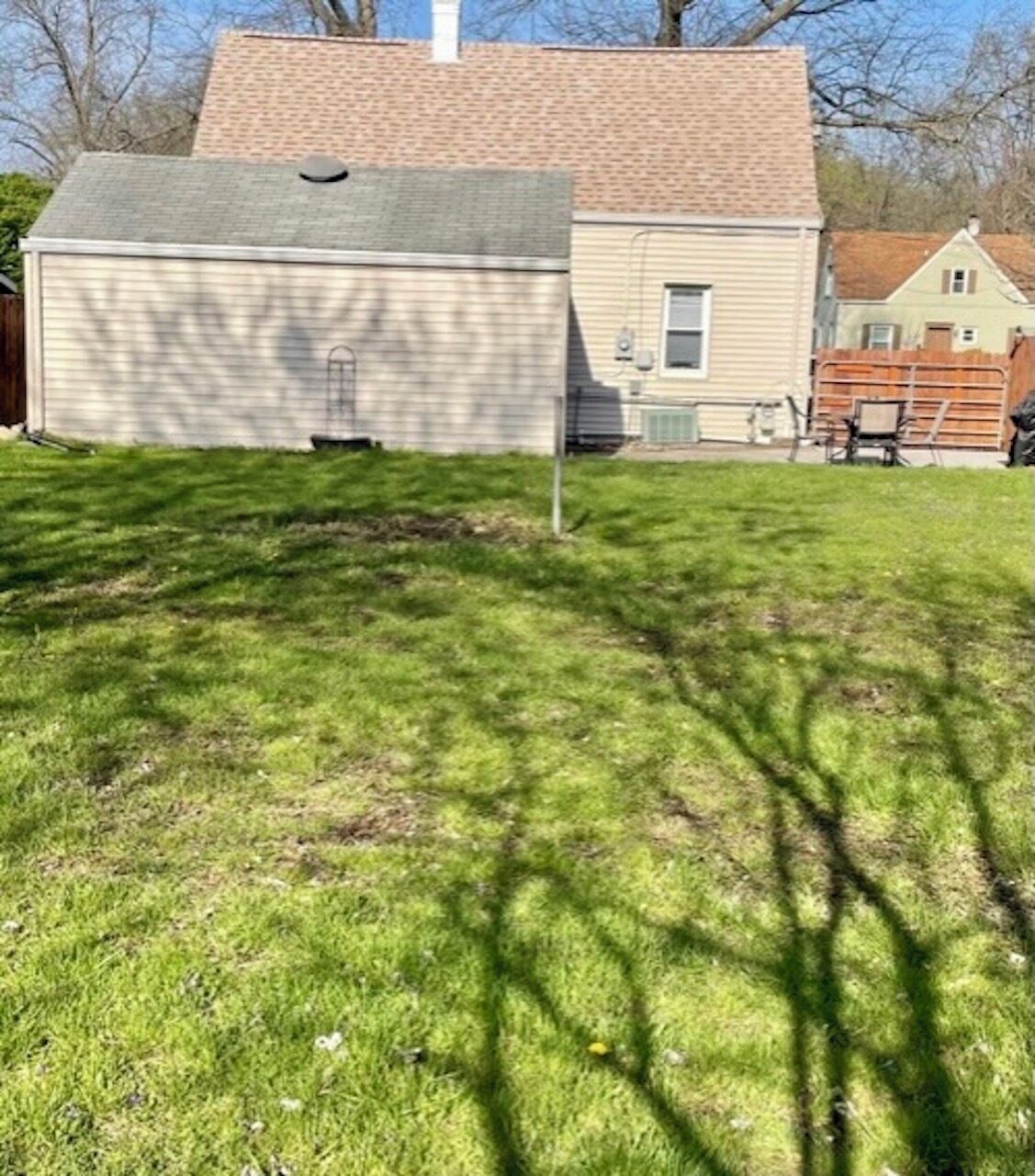A grassy yard with a shed and a house in the background.