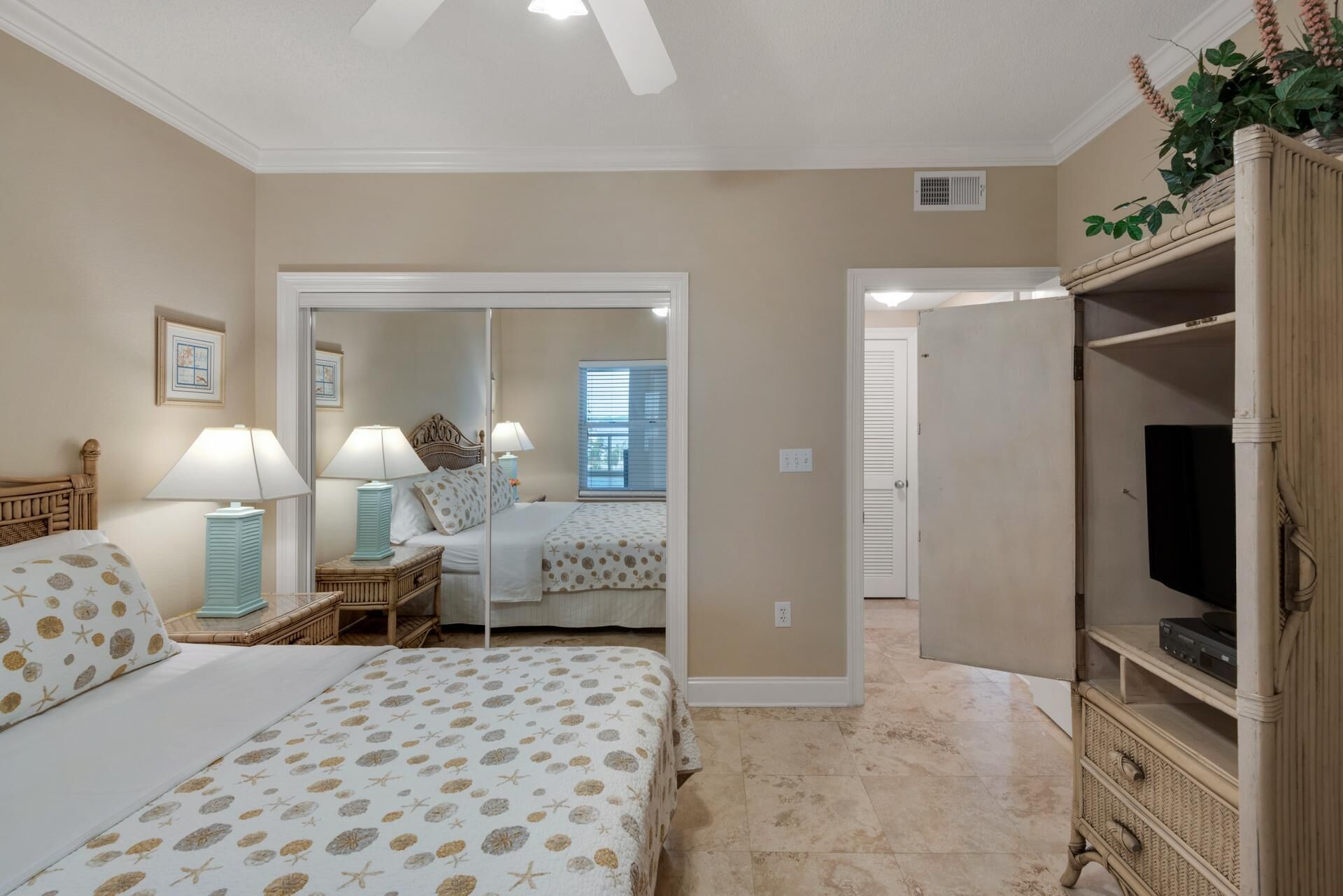 A bedroom with two beds, a TV, and a mirror.