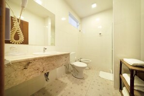 A modern bathroom with a marble countertop, two toilets, a large mirror, and a wooden shelf with towels. - Hotel Mil Flores (Braganca Paulista)