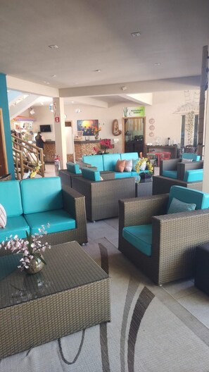 A hotel lobby with a seating area featuring wicker furniture and a teal sofa. - Hotel Mil Flores (Braganca Paulista)