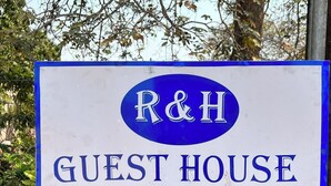 Placa de uma pensão com as letras 'R&H' em um oval azul.