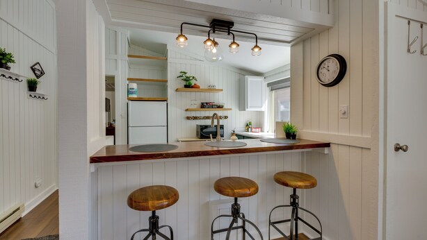 A kitchen with a wooden countertop, three stools, a hanging light fixture, and a clock on the wall. - Cozy La Veta Condo: Walk to Cuchara Mountain Park! (La Veta)