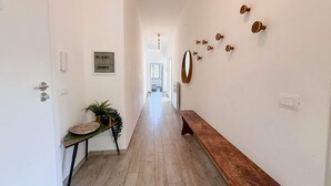 A hallway with a wooden bench, a round mirror, and wall-mounted light switches. - Verdemare  (Chiavari)