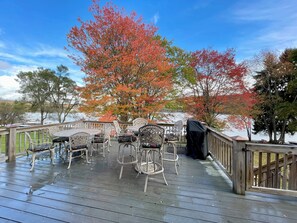A wooden deck with outdoor furniture and a view of a lake. - A Shore Thing by Taylor Made Deep Creek (McHenry)