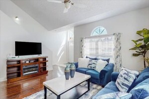 Relax in this stylish living room with a flat-screen TV, comfortable sofa, and large window.