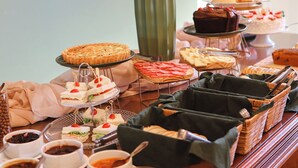 A buffet table with various food items and a vase of dried plants. - Hotel Triveneto Gramado (Gramado)