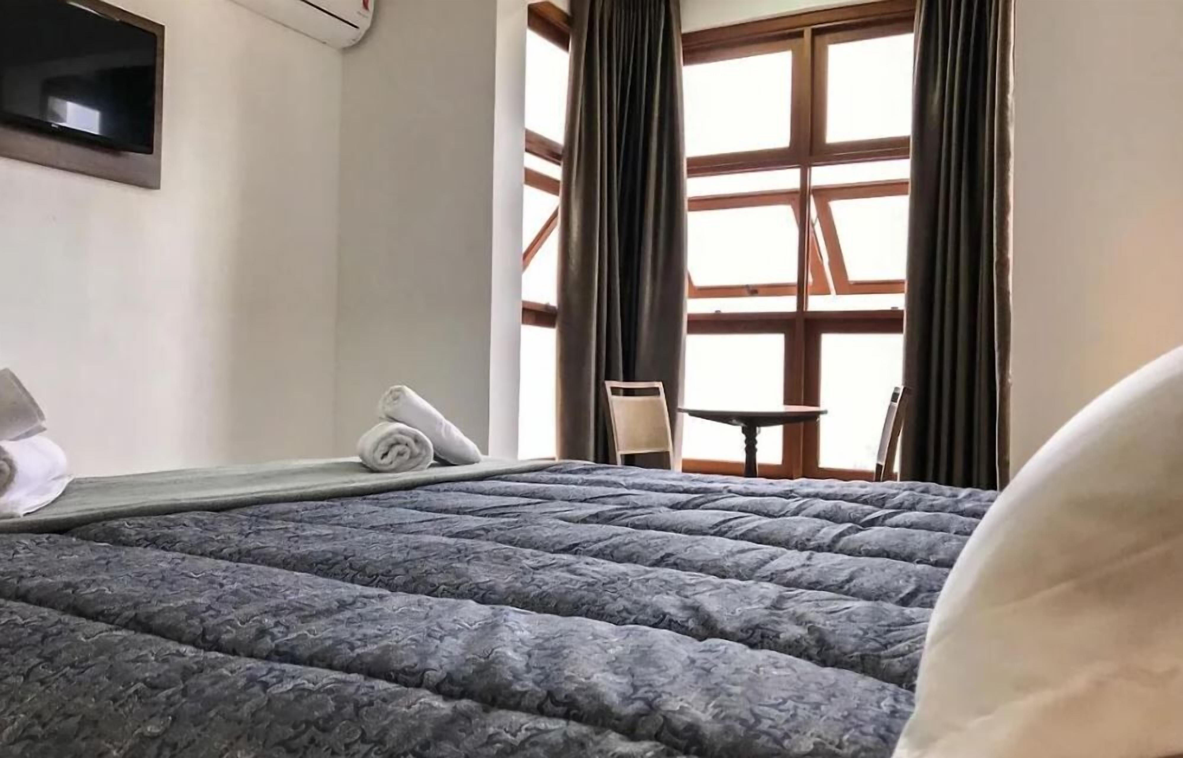 Hotelkamer met een groot bed, een flatscreen televisie aan de muur en een raam met gordijnen.