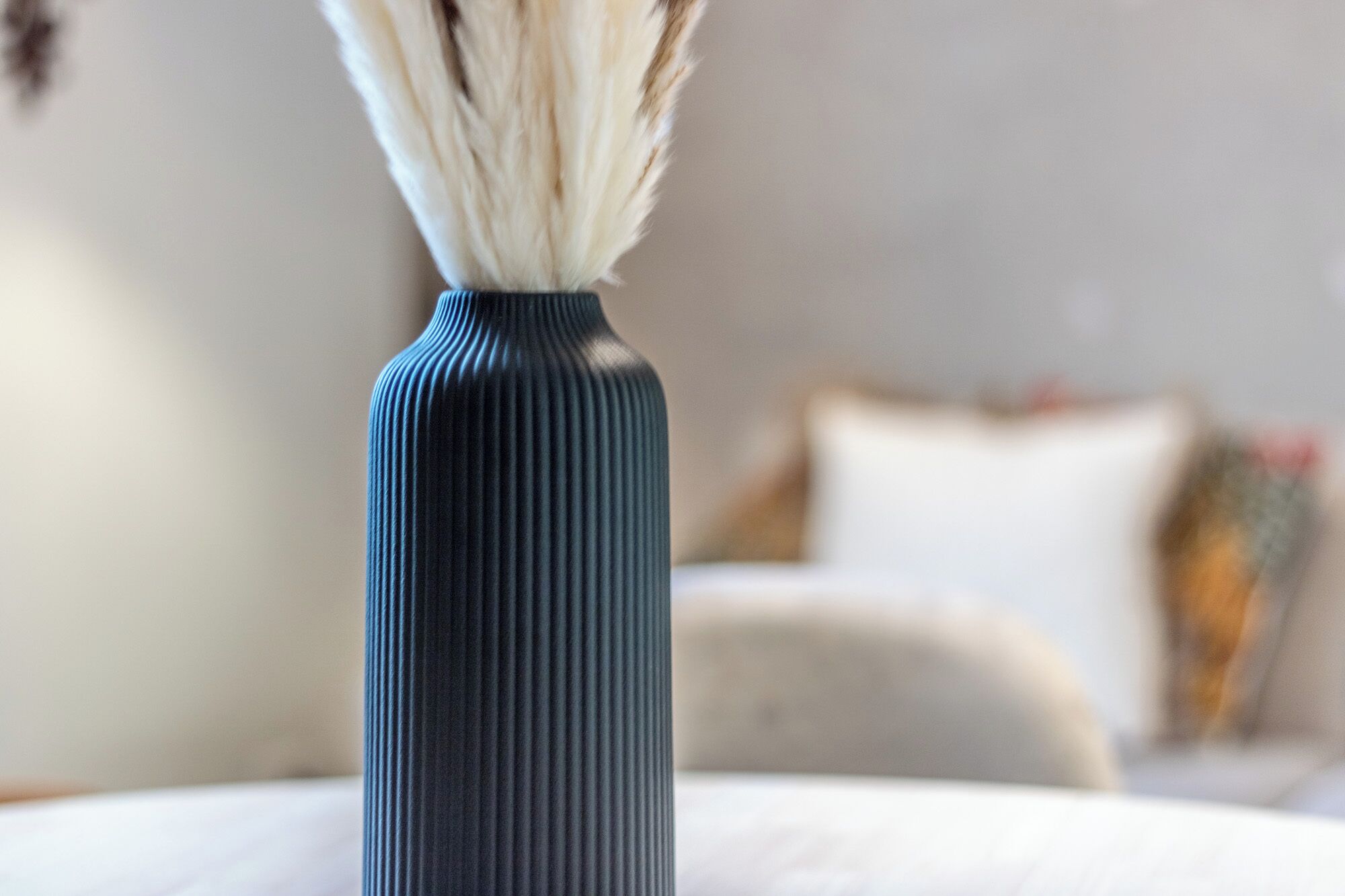 Een donkerblauwe vaas met geribbelde textuur op een witte ondergrond.