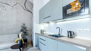 Cocina moderna con microondas integrado, un lavabo y una tetera en la encimera.
