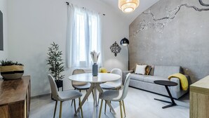 Una sala de estar moderna con una mesa redonda de comedor, dos sillas, un sofá gris y una pequeña mesita auxiliar.