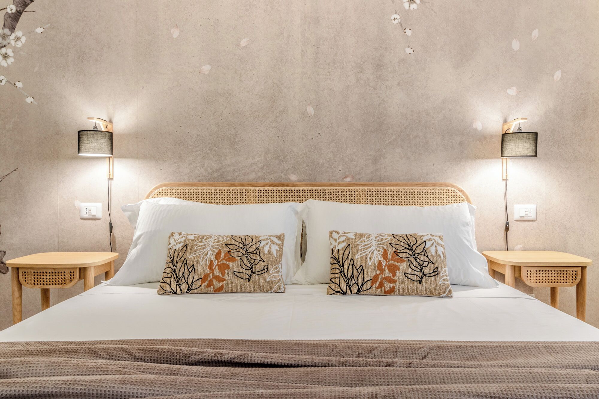 A bed with two pillows, a wooden headboard, and two bedside tables with lamps.