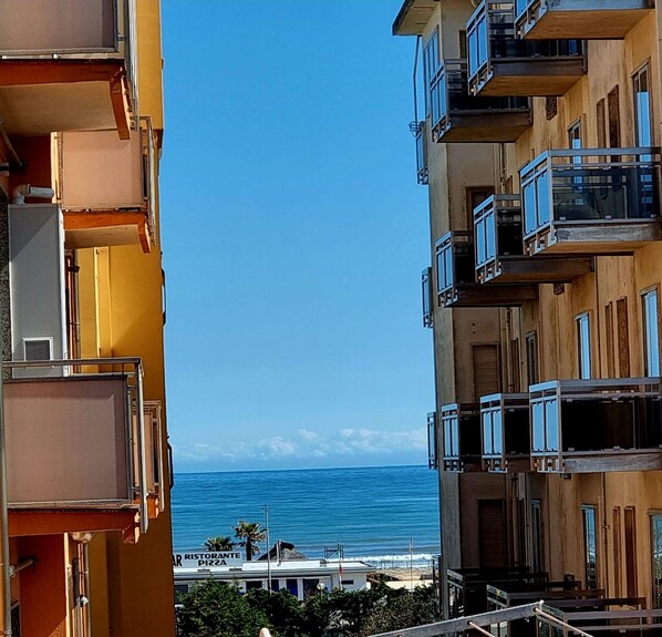A multi-story building with balconies overlooking a beach.