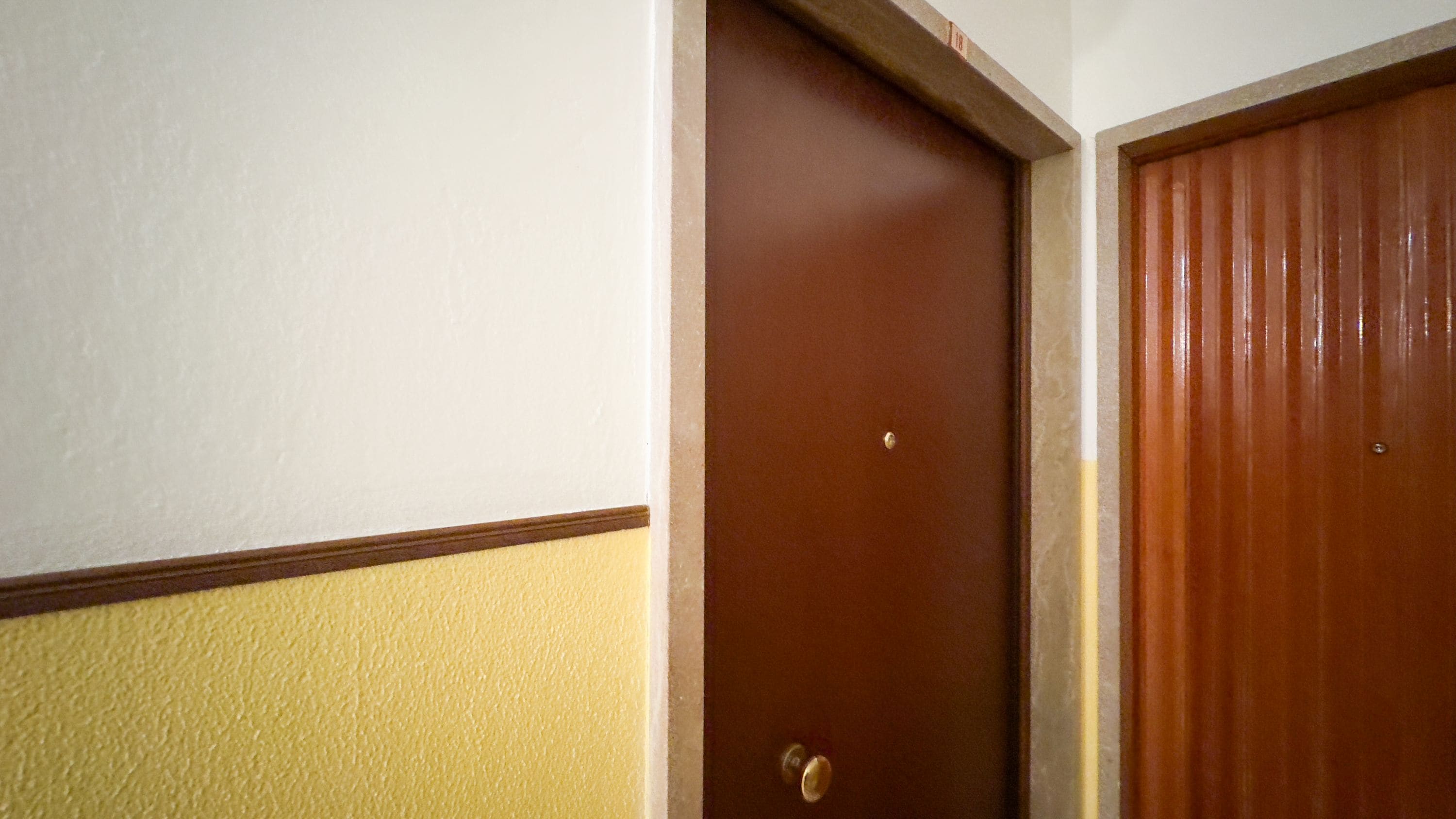 A door with a brass doorknob and a small hole in the center.