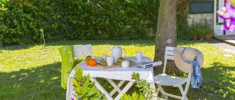A picnic setup with a table, chairs, and a basket under a tree.
