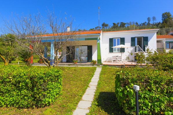 A two-story house with a covered porch, a small garden, and a clear sky. - Estate4home - Villa Corinna (Massa Lubrense)