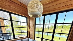 A cozy room with a large window, a table, and seating area. - Chalet en Bordure du Canal le 236 (Saint-Anicet)