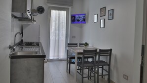 Eine moderne Küche mit eingebautem Herd, einer Essecke mit Tisch und Stühlen sowie einem an der Wand befestigten Fernseher.