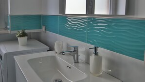 Ein modernes Badezimmer mit einem großen Waschbecken, einem Spiegel und einem Fenster über dem Spiegel.