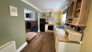 A compact kitchen with a built-in oven, a microwave, and a sink. There's a blue chair and a fireplace in the adjacent living area.
