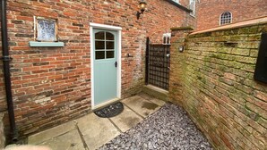 A brick building with a light blue door, a black gate, and a small window with a decorative pattern.
