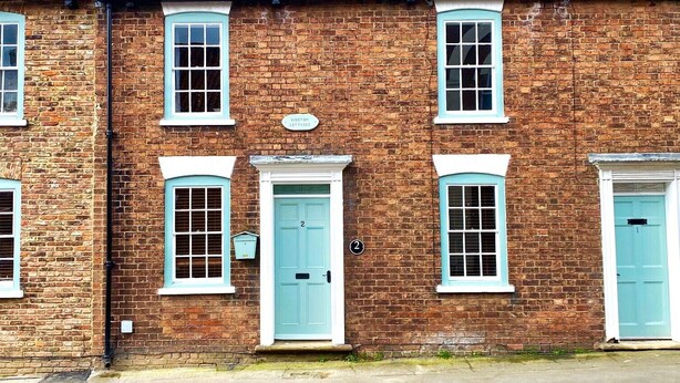 A brick building with two doors and windows, each with a light blue frame.