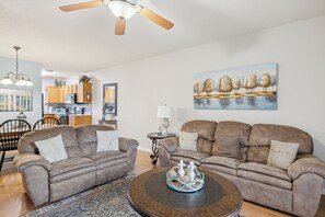 A living room with two sofas, a coffee table, and a painting on the wall.