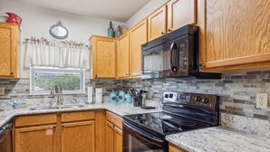 A kitchen with wooden cabinets, a stainless steel oven, a microwave, and a granite countertop. - 2 Bedroom Condo with River View | Located in Pigeon Forge | Sleeps 6 (Pigeon Forge)