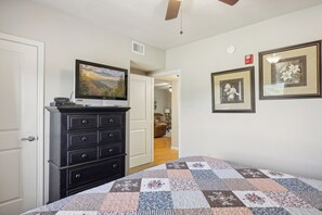 A bedroom with a bed, dresser, TV, and framed pictures on the wall.