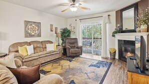 A living room with a brown leather sofa, a matching armchair, a fireplace, and a ceiling fan.