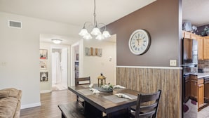 A modern kitchen with a built-in refrigerator, wooden cabinetry, and a dining area with a dark wooden table and benches.