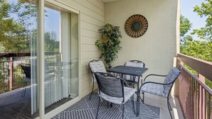 A balcony with a table and chairs, a potted plant, and a decorative wall piece.