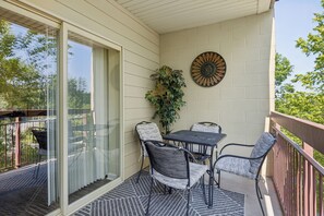 Un balcon avec une table et des chaises, une plante en pot et un élément décoratif mural.