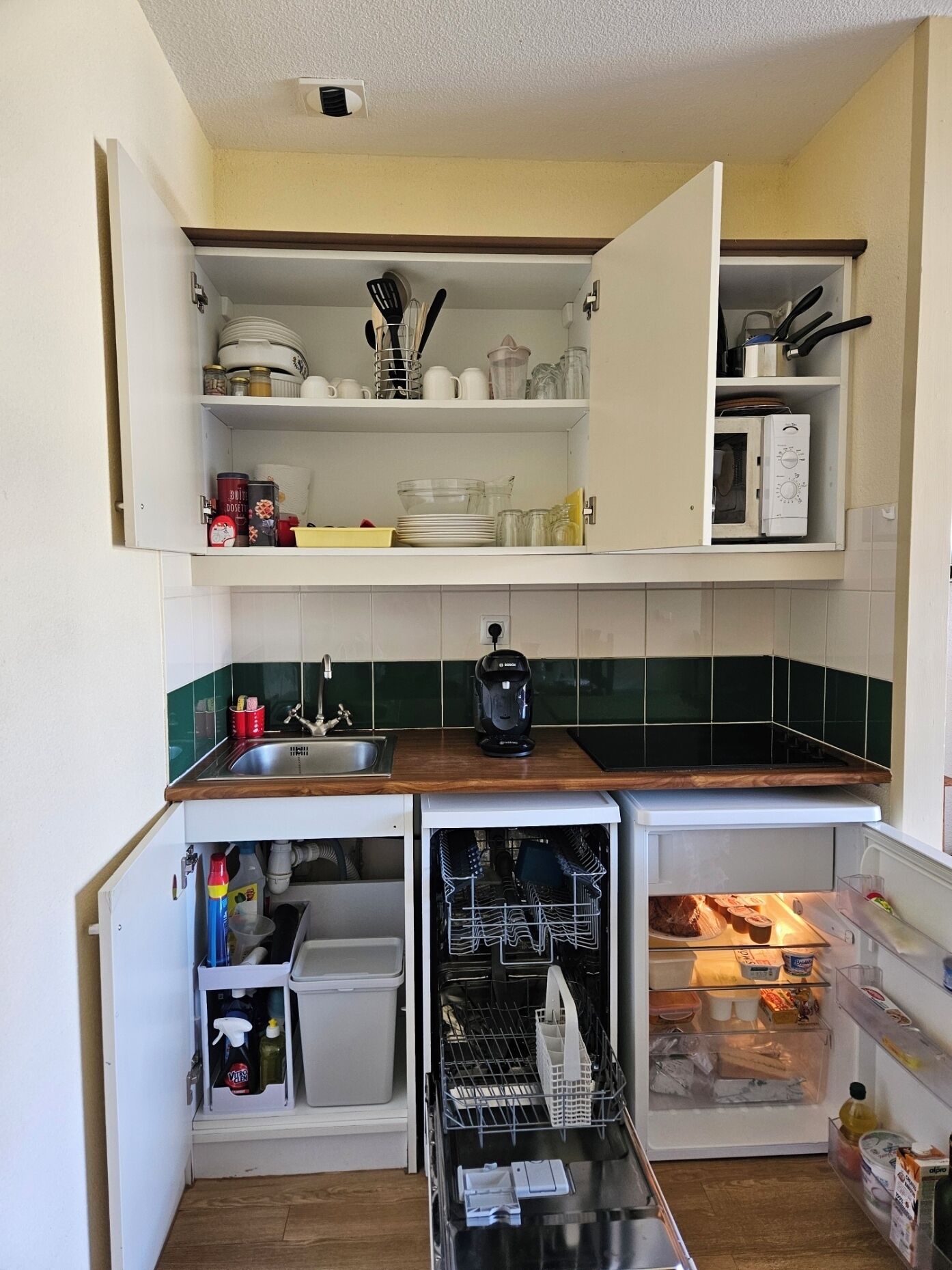 Una cocina compacta equipada con microondas, cafetera y lavavajillas.