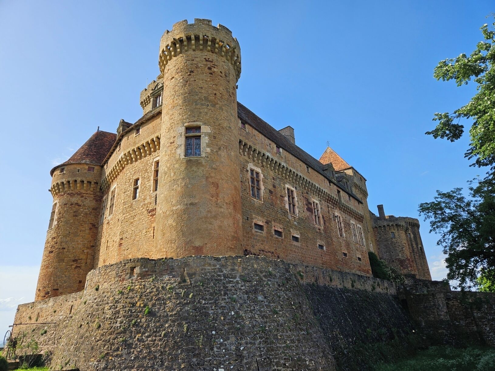 A historic castle with a round tower, stone walls, and a fortified entrance.