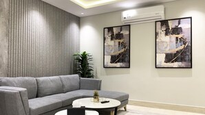 Un salon moderne avec un canapé d’angle gris, une table basse ronde et deux tableaux abstraits accrochés au mur.