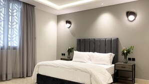 Une chambre à coucher moderne avec un grand lit, deux tables de chevet et une tête de lit.