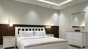 A modern bedroom with a bed, nightstands, a dresser, and a mirror.