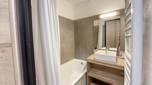 A bathroom with a bathtub, a sink, and a mirror. - 200m from ski slopes, 1st floor, balcony, tv, ski locker, 26m², La Rosière (La Rosière Montvalezan)