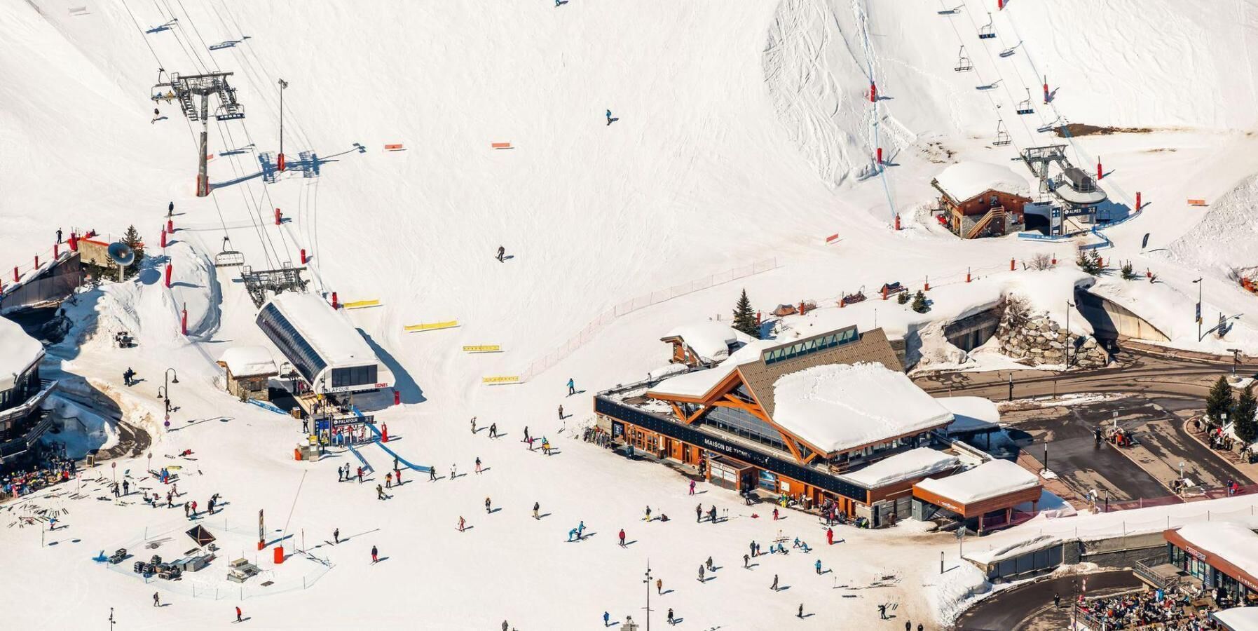 Estância de esqui com edifício principal, teleféricos e paisagem coberta de neve.