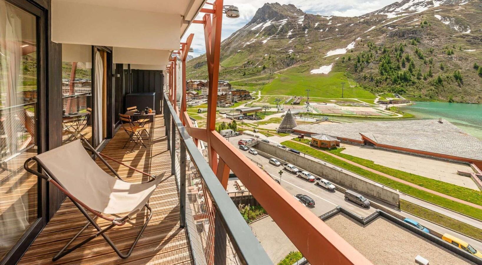 Un balcone con una sedia, un tavolo e vista su una montagna e un lago.