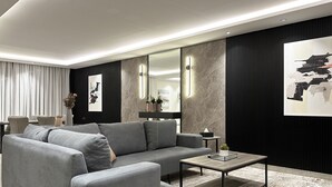 A modern living room with a grey sofa, a coffee table, and a large abstract painting on the wall. - Kease Malqa 31-10 Luxury Gold  AG23 (Riyadh)